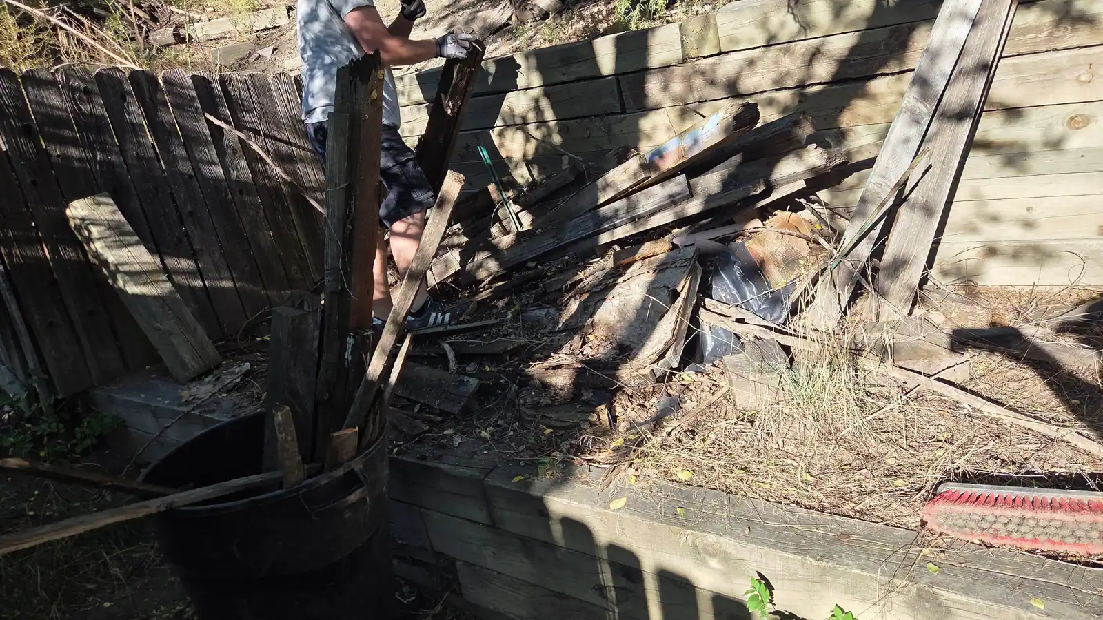 Tearing out an old wood fence and timbers along a retaining wall