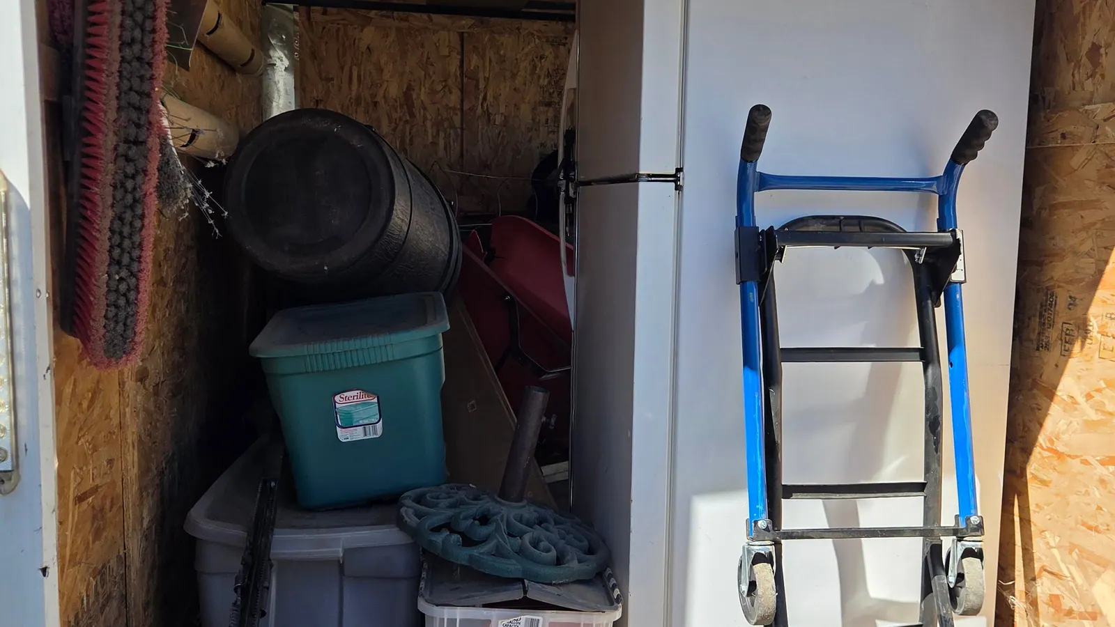 A refrigerator and storage bins loaded in the cargo trailer with a hand truck