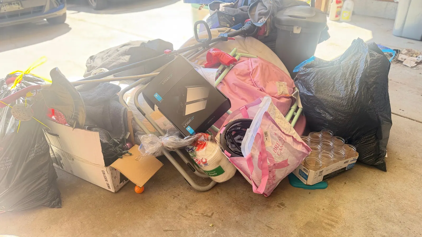Bags and boxes and household junk piled on a garage floor