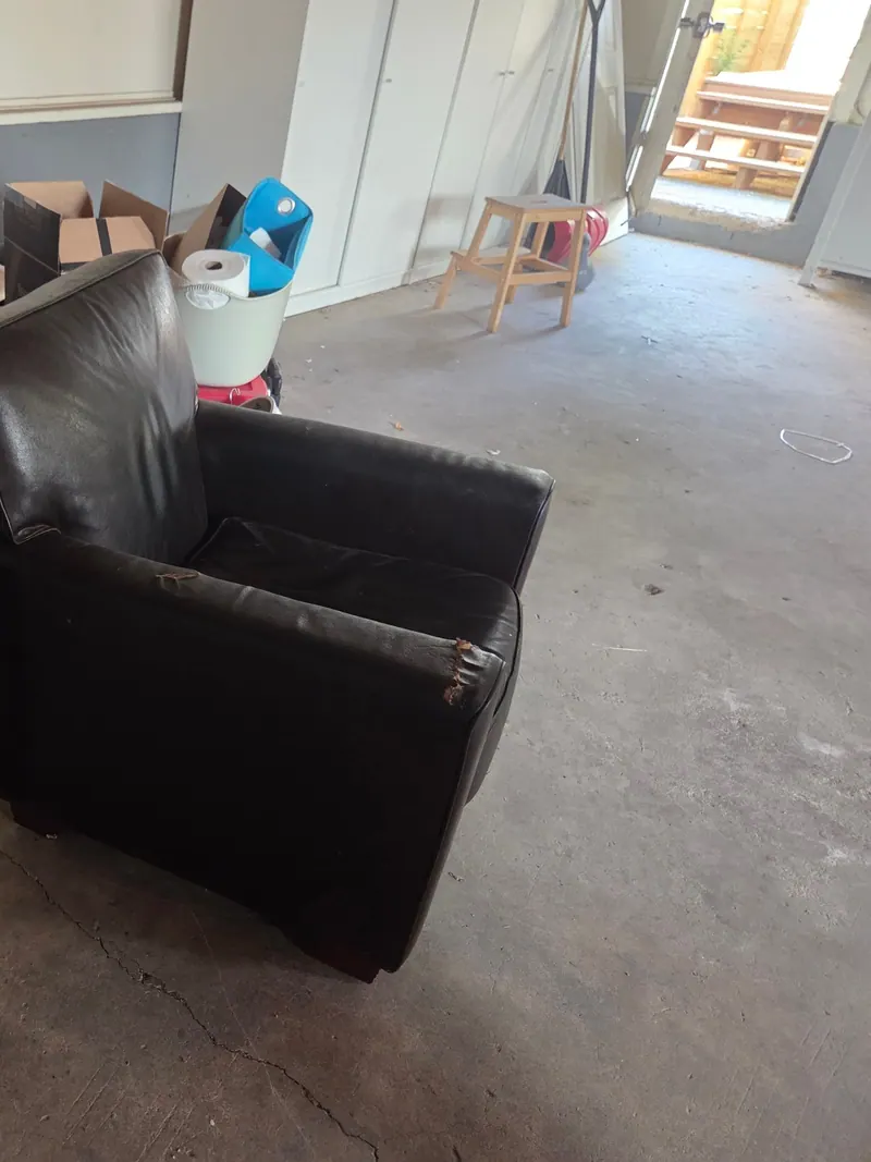 A desk a leather chair and boxes of household items to clear out