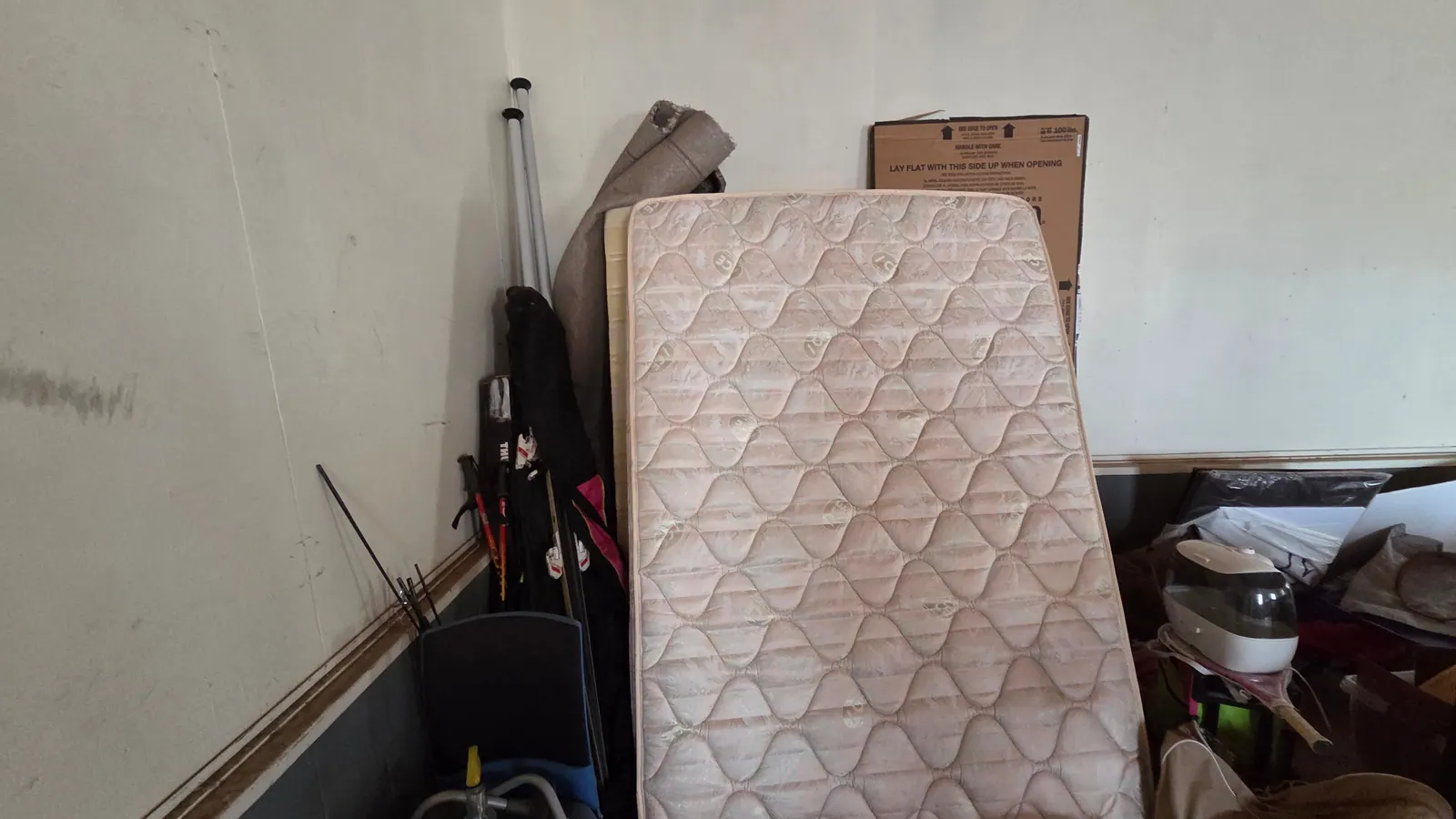 An old mattress leaned against a garage wall waiting to be hauled