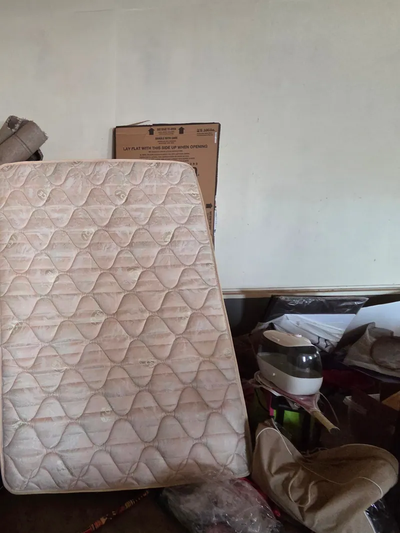 An old mattress leaned against a garage wall waiting to be hauled