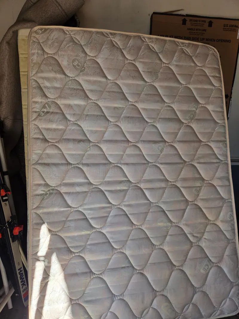 A worn out mattress standing on end ready for pickup
