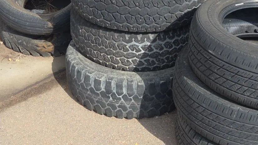 Old tires stacked against a fence for pickup