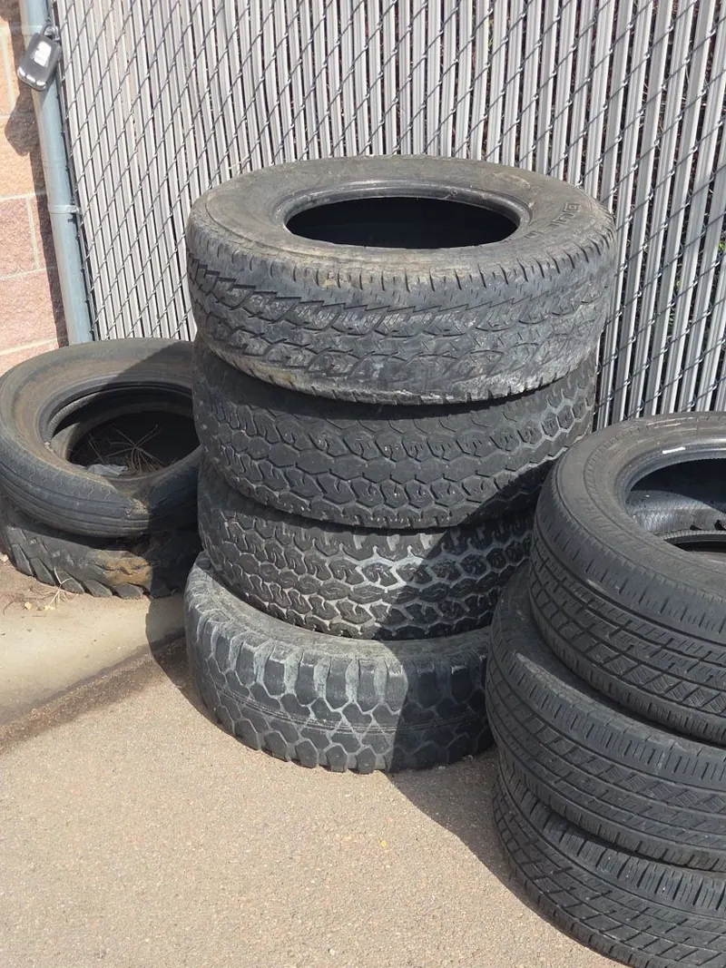 Old tires stacked against a fence for pickup